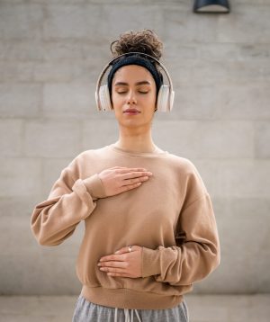 one woman adult caucasian female using headphones for online guided meditation practicing mindfulness manifestation with eyes closed stand outdoor real people self care concept copy space
